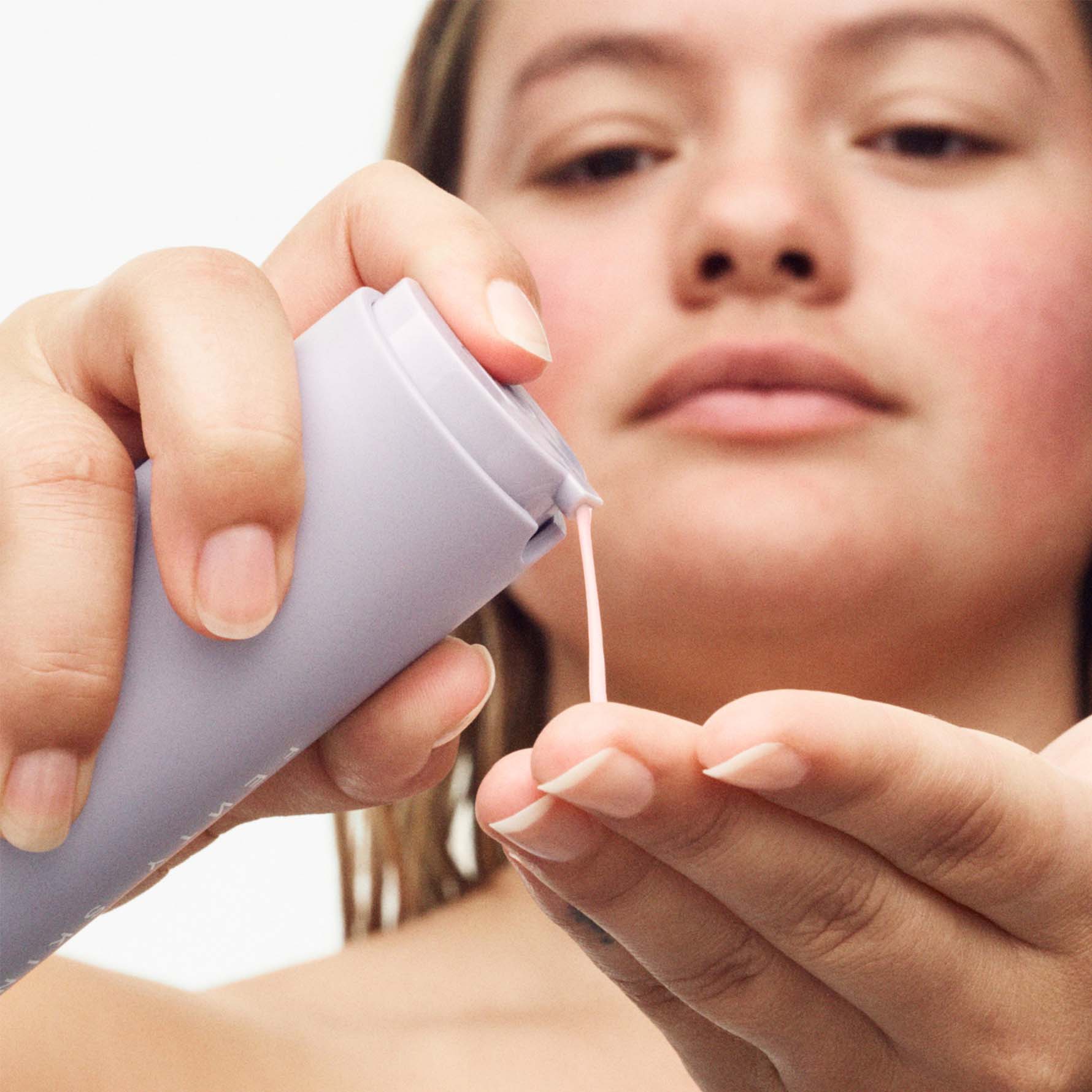Model squeezing Hydra Vizor Moisturizer into hands,